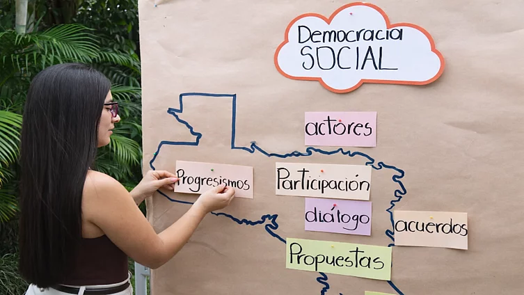 Mujer joven haciendo metaplan con conceptos de democracia social.