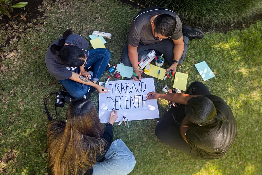 Grupo de jóvenes haciendo cartel sobre trabajo decente.